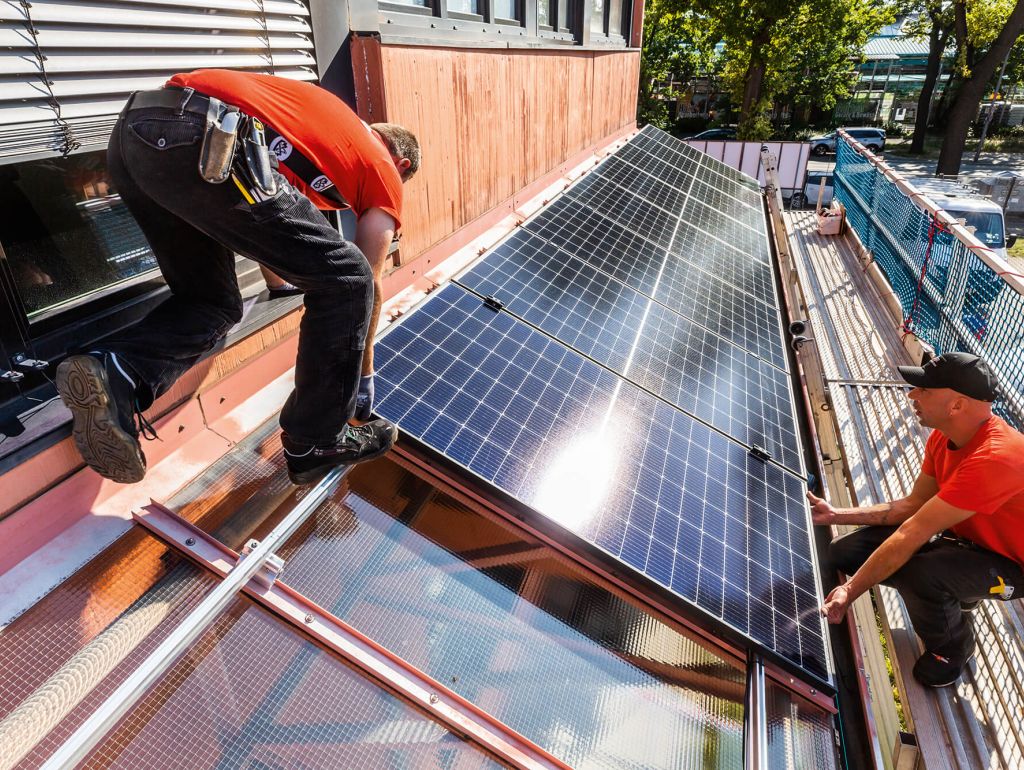 2 Männer befestigen eine Solarzelle auf einem Hausdach