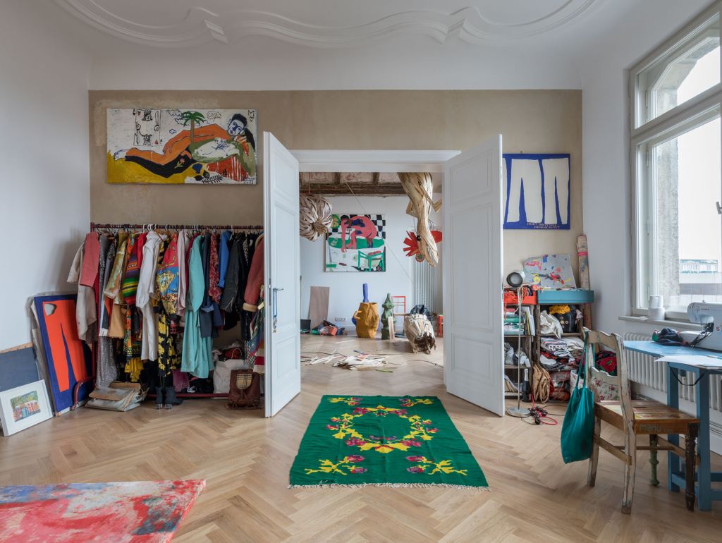 Ein Raum, der mit verschiedenen Kleidungsstücken und Kunstwerken gefüllt ist, die die Wände schmücken.