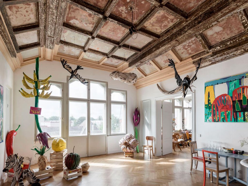 Ein lichtdurchflutetes Atelier mit großen Fenstern und Kunst an den Wänden 