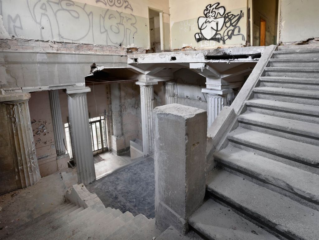 Der innere und baufällige Teil eines verlassenen Gebäudes mit Säulen sowie einer mit Graffiti beschmierten Wand