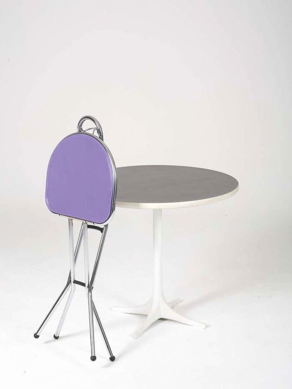 Ein Klappstuhl aus Metall lehnt ein einem Tisch