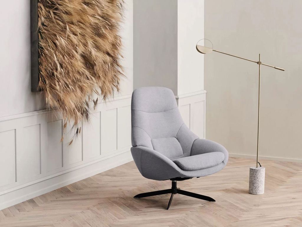 Ein Wohnraum mit einem gemütlichen Sessel, einer modernen Stehlampe und Ähren als Wanddeko