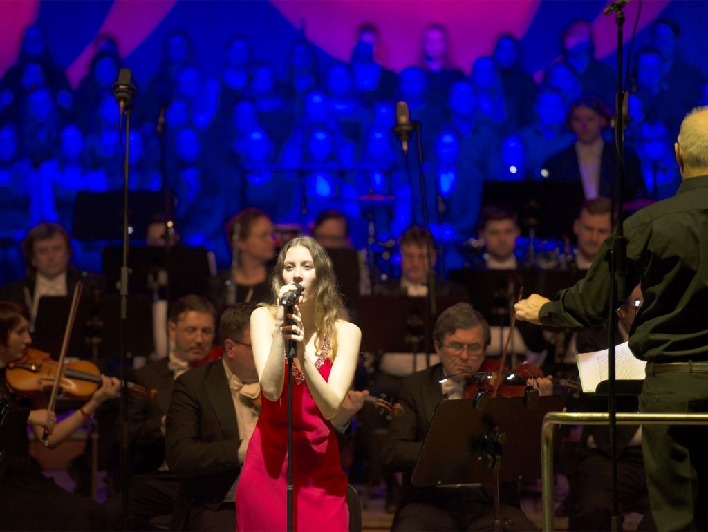 Sängerin auf der Bühne mit Orchester im Hintergrund
