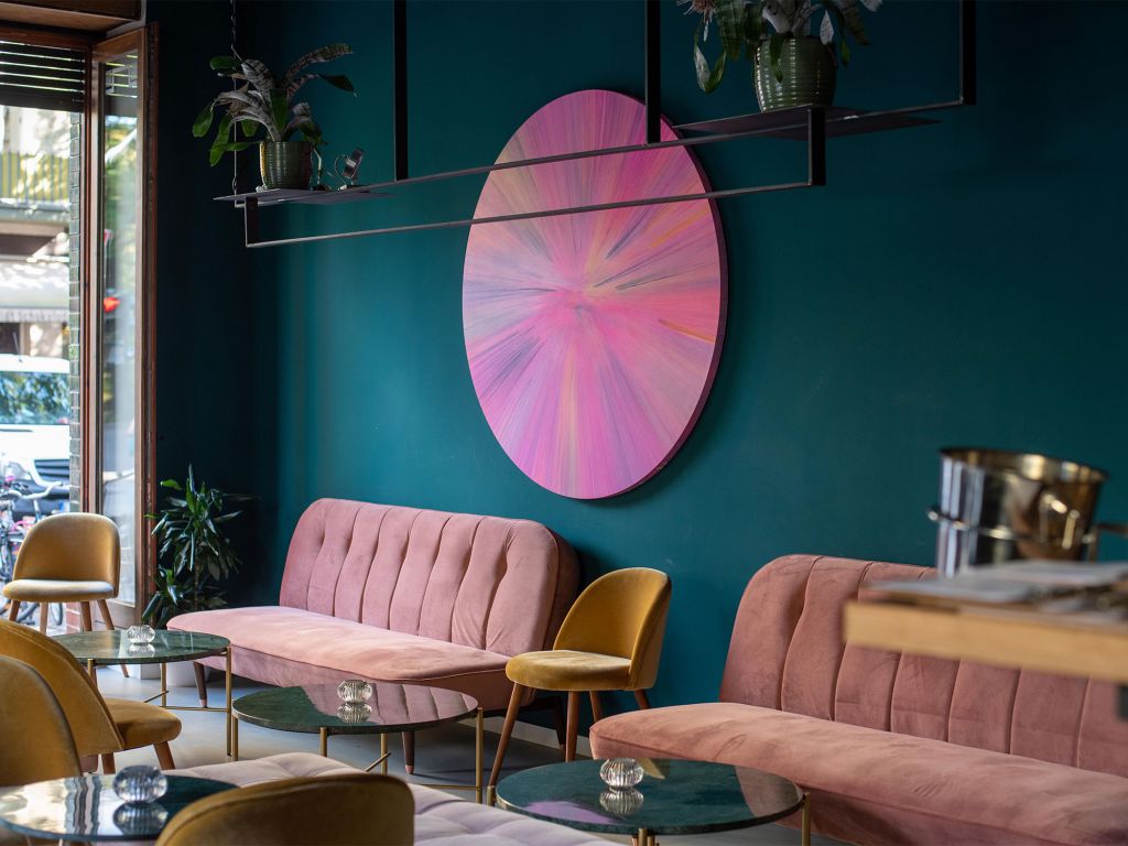 Gemütliches Restaurant Interreur mit grünen Wänden rosa Sofas und rosa Kunst an den Wänden 