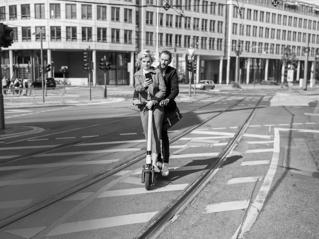 Eine Frau und ein Mann fahren zu zweit auf einen E-Roller